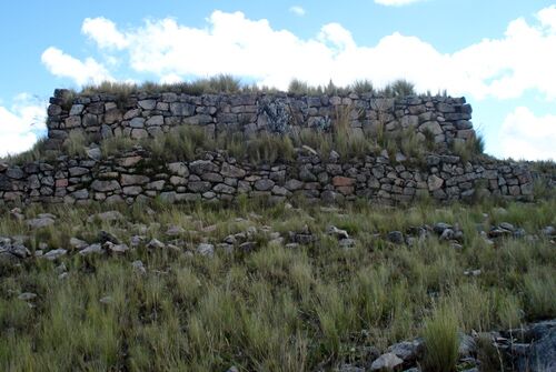 Incapirca Waminan ushnu is located on a rounded mountaintop on the altiplano near the city of Ayacucho and offers a remarkable view of major mountain peaks and ranges such as Uripe, Condoray, Qarawarasu and Rasuwillca.The ushnu here is situated on the summit of the mountain and comprises three superimposed platforms. The basal one is little more than a rectangular outline of rocks, barely a single rock in height but measuring 32.7m by 18.5m. The second platform consists of a single faced wall, measuring 24.5 m by 11.4m. The third and final platform is contained within a double-faced wall, and measures 22.8m in length by 9.6m in width. The walls are built out of grey andesite which appears to have been quarried nearby. © Trustees of the British Museum