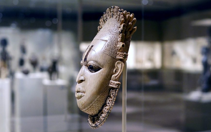 <em>Queen Mother Pendant Mask</em> (Iyoba), 16th century, Edo peoples, Court of Benin, Nigeria, ivory, iron, copper, 23.8 x 12.7 x 8.3 cm (The Metropolitan Museum of Art, New York)