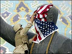 U.S. soldiers cover the face of a statue of Saddam Hussein with an American flag before toppling the statue in downtown in Baghdad, Iraq. (AP/Jerome Delay)