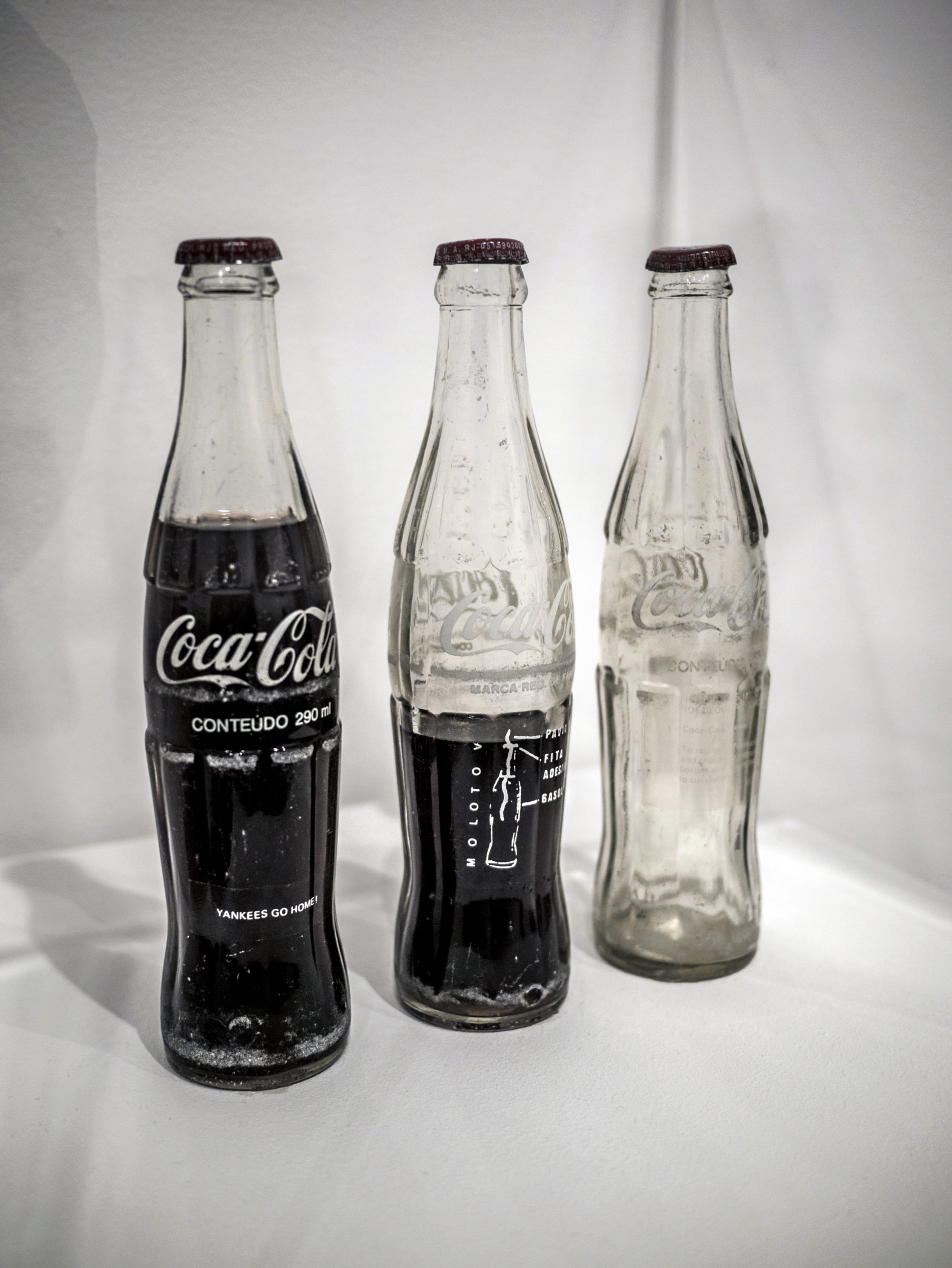 Cildo Meireles, Insertions into ideological circuits: Coca-Cola Project, 1970, 3 glass bottles, 3 metal caps, liquid and adhesive labels with text, each: 25 × 6 × 6 cm (photo: Yann Caradec, CC BY-SA 2.0)