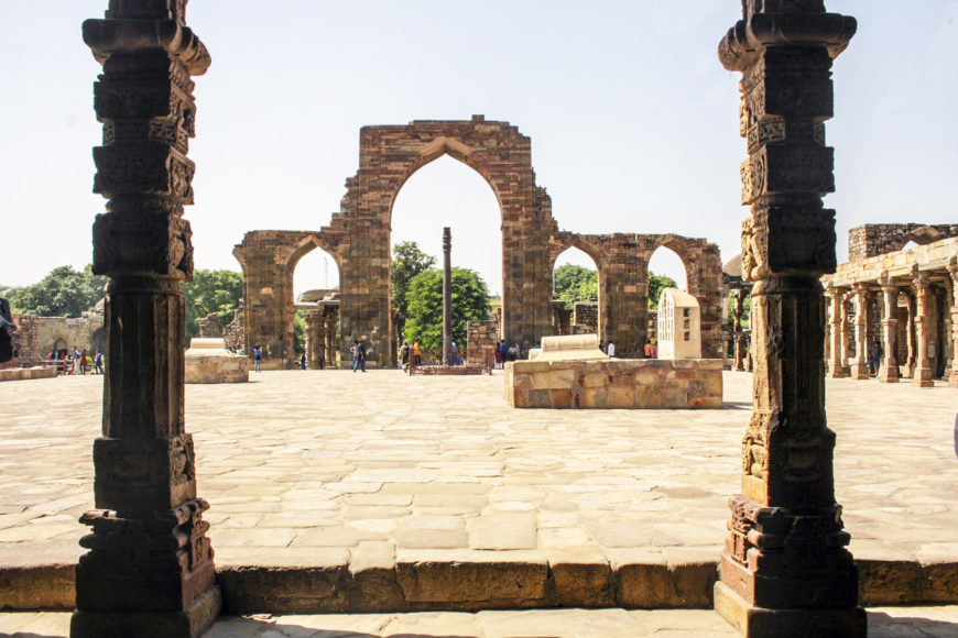 The courtyard of the Quwwat-al-Islam mosque, c. 1192, Qutb archaeological complex, Delhi (photo: Indrajit Das, CC BY-SA 4.0). In the foreground are pillars of the colonnaded walkway and in the background is the c. 4th – 5th century iron pillar and the 12th century screen and prayer hall.