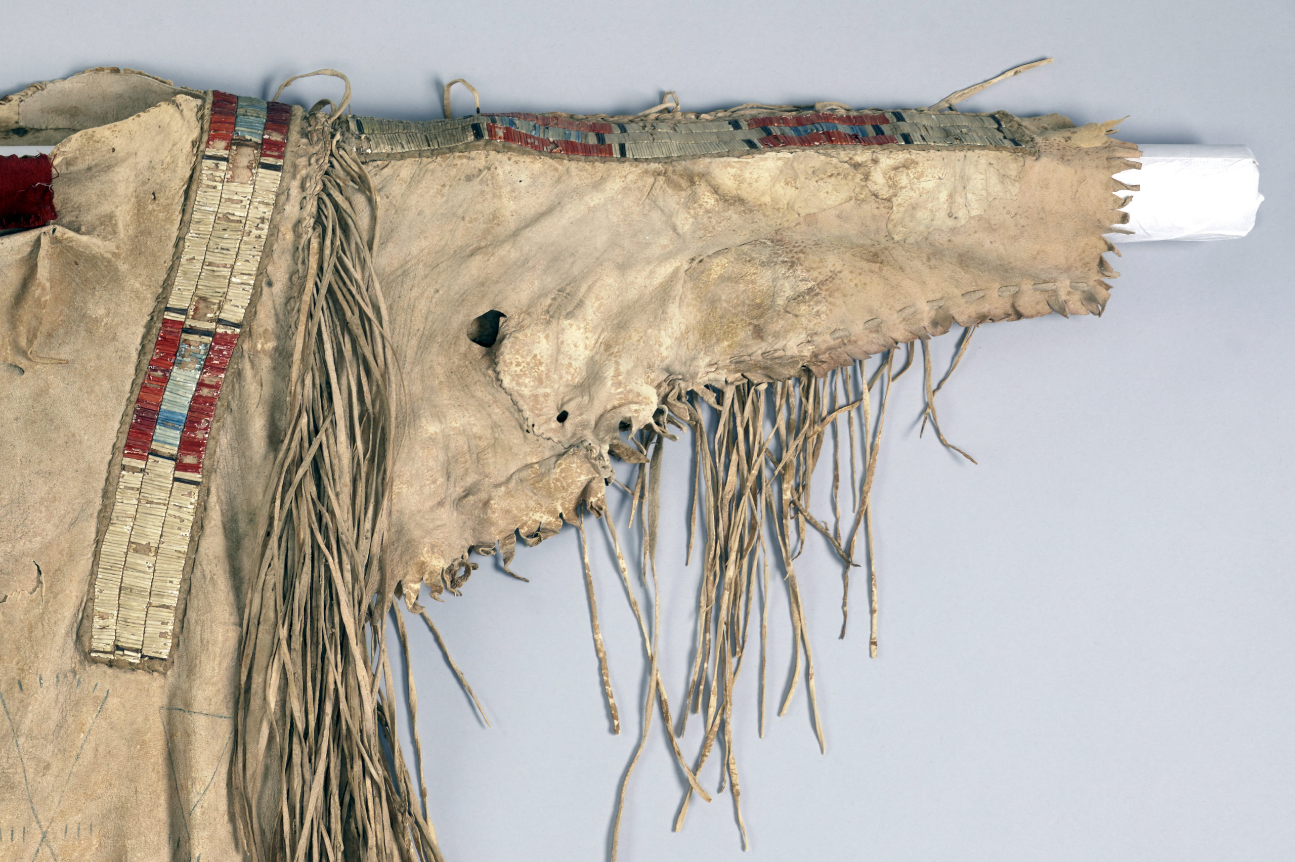 Detail of a sleeve, quilled war shirt, c. 1800-1820. Native tanned hide, porcupine quills, red trade cloth, dyes, and sinew. 34 x 43 in. (Denver Art Museum)
