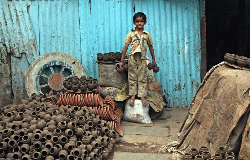 A boy stands in a potter’s yard, holding traditional clay cups (photo: Meena Kadri, CC BY-NC-ND 2.0)