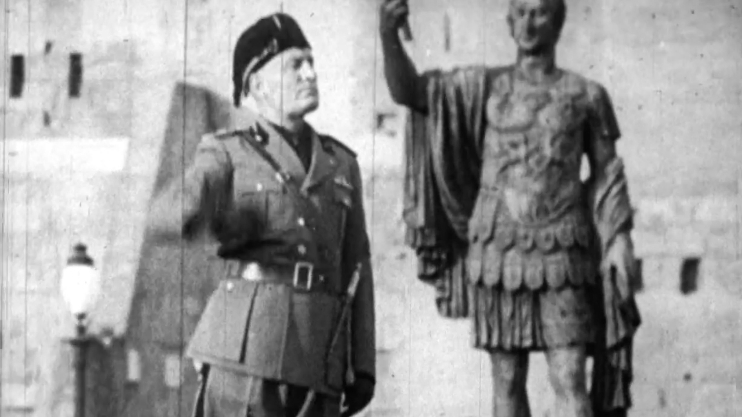Benito Mussolini reviewing a military parade beside a statue of a Roman emperor, 1943, newsreel still