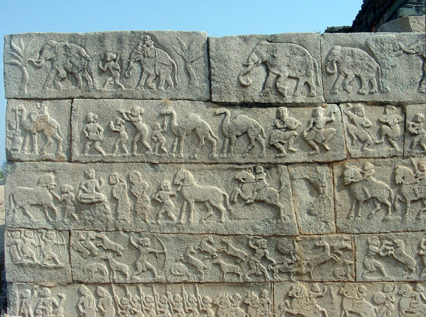 Reliefs on the west end of the south face of the royal platform. From bottom to top, we see: 1) the king reviews a military procession; 2) a hunting scene; 3) horsemen; 4) camels, musicians, and dancers; and 5) elephants, in the city of Vijayanagara (photo: Vipulvaibhav5, CC BY-SA 4.0)