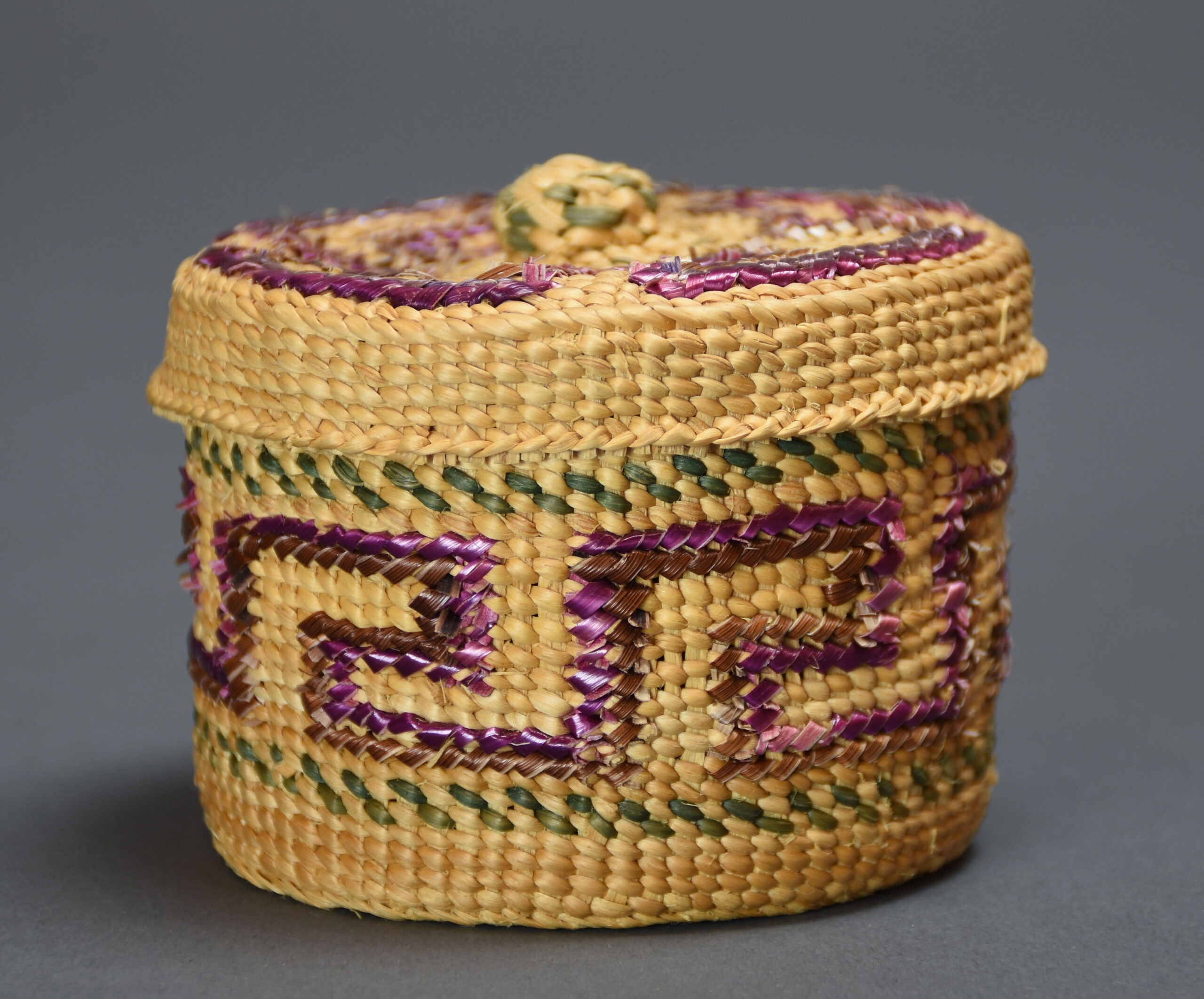 Selina Peratrovich, Haida, Kigw, Spruce Root Basket, 1977, twined spruce root basket with lid. Purple “cresting wave” design in false embroidery in center of basket flanked by two bands of “strawberry” design woven into the basket with green dyed spruce root (Ketchikan Museums: Tongass Historical Society Collection, THS 77.7.8.1 A&B)