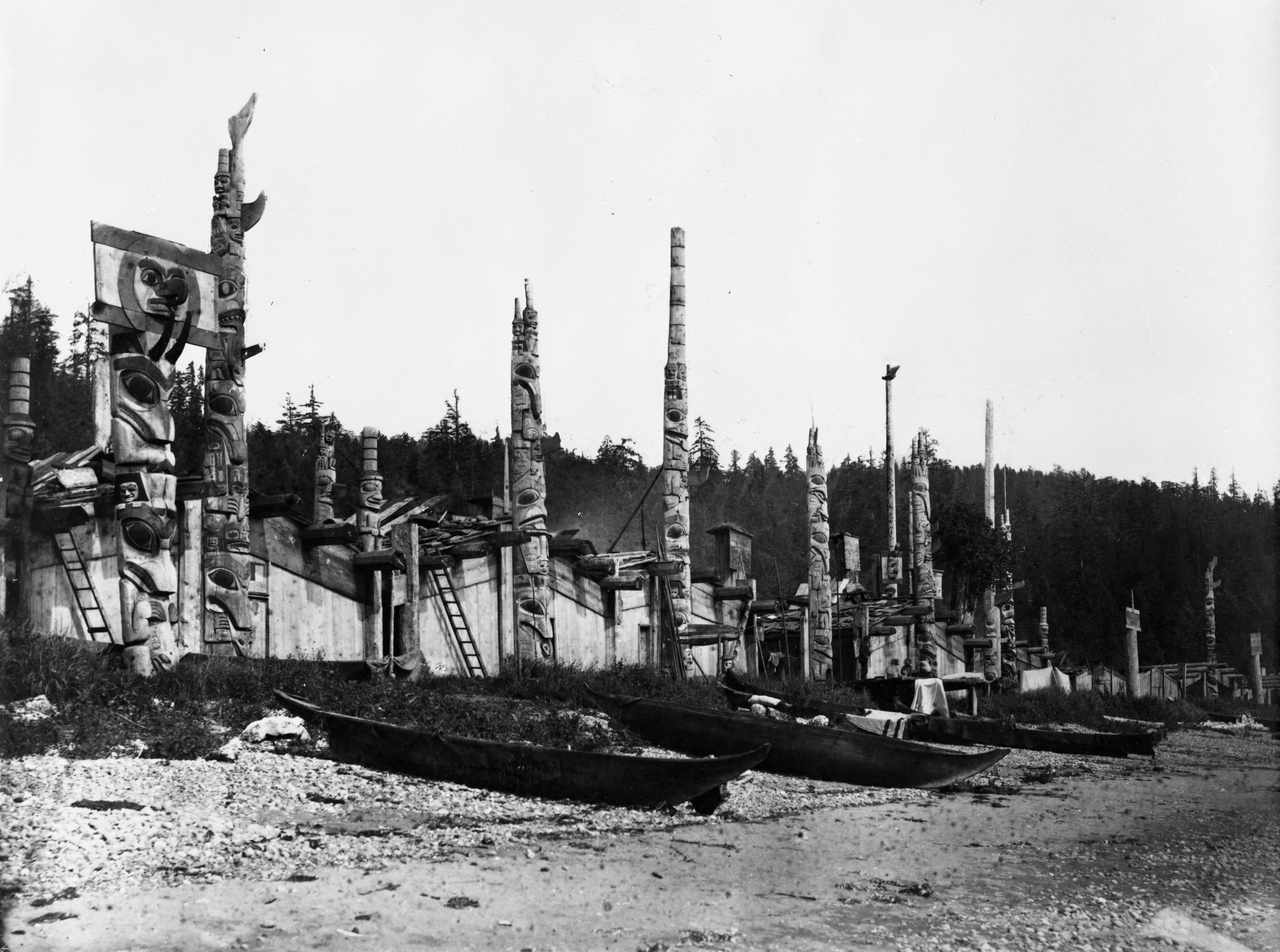 The Haida village of Skidegate in 1878, showing monumental poles, clan houses, and canoes on the beach. Photo by George M. Dawson.