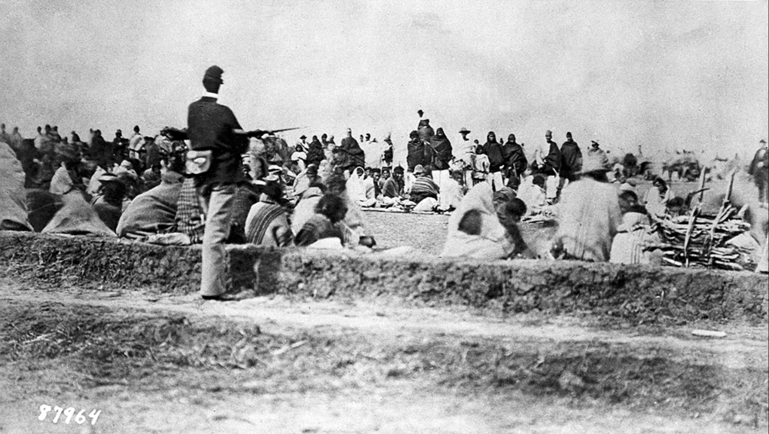 Diné (Navajo) captives under guard, Fort Sumner, New Mexico, c. 1864–68 (<a href="https://econtent.unm.edu/digital/collection/acpa/id/936/rec/1" target="_blank" rel="noopener">New Mexico History Museum</a>, photo: United States Army Signal Corps)