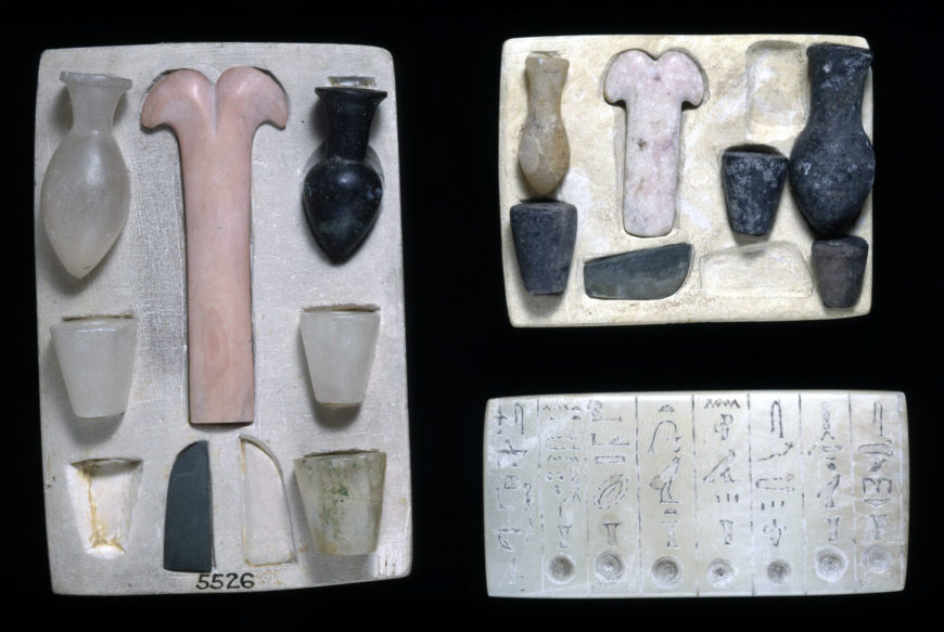 Model of equipment for Opening of Mouth Ceremony: five vessels (calcite and limestone), a small knife blade and a 'peseshkef' implement (schist and limestone) set into depressions of limestone tablet, 6th dynasty, calcite, limestone, and schist, Egypt (© Trustees of the British Museum)