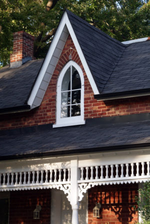 Detail of a pointed arch or Gothic window in the central gable of the porch. The woodwork on the verandah is visible below.
