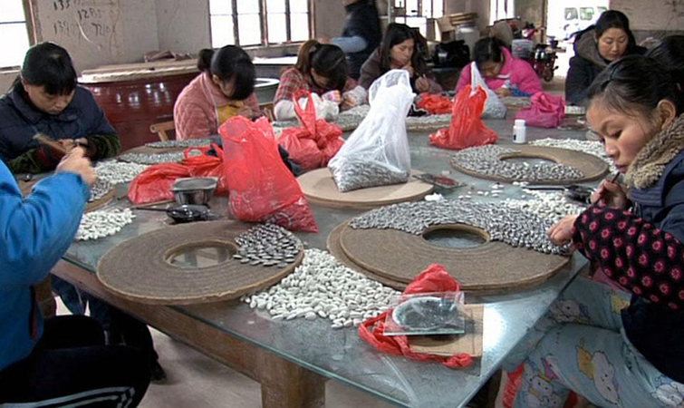 Some of the 1,600 highly skilled craftspeople from Jingdezhen hired to create and paint porcelain sunflower seeds