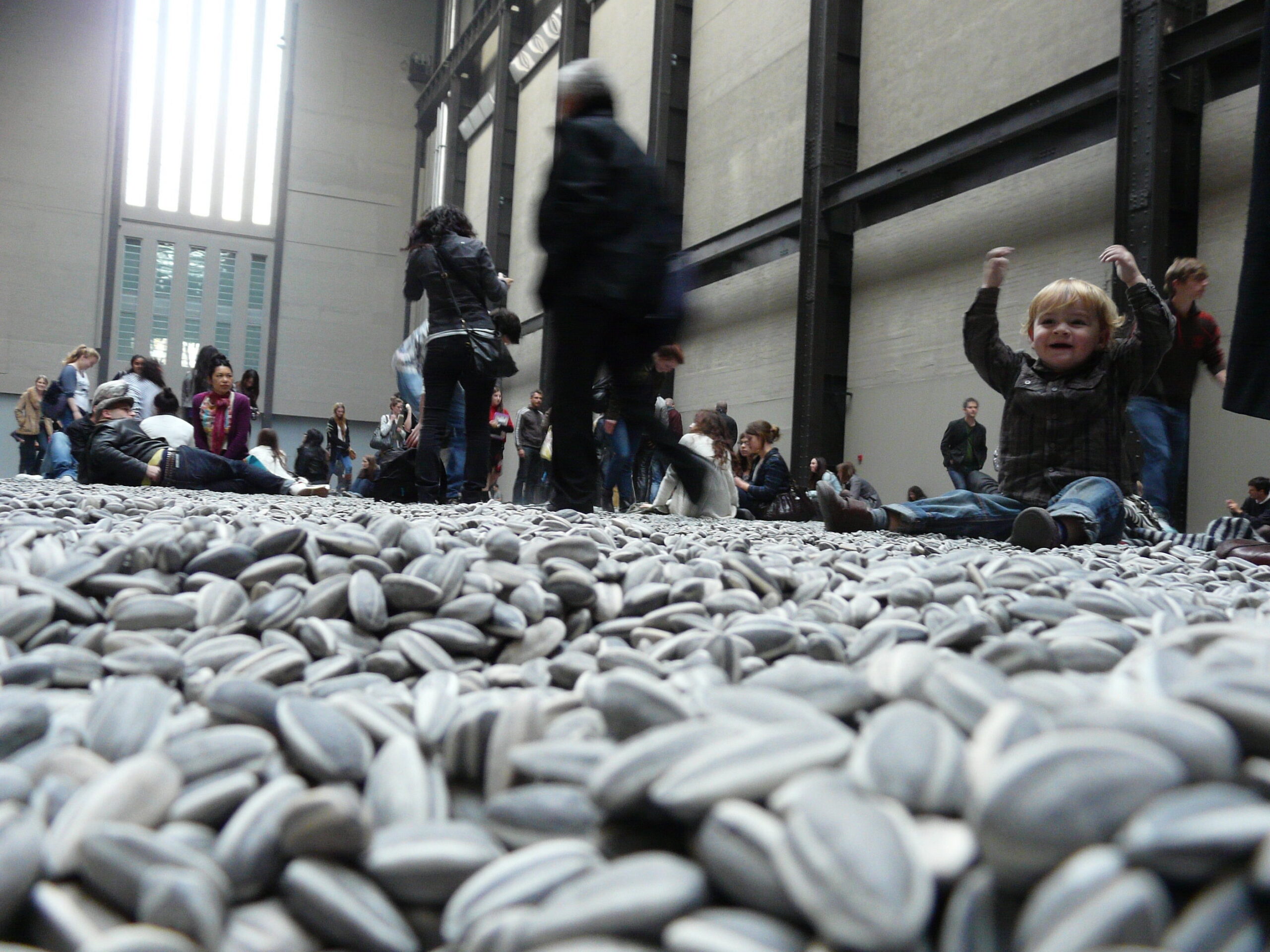 Visitors interacting with the installation, Ai Weiwei, Kui Hua Zi (Sunflower Seeds), 2010, one hundred million hand-painted porcelain seeds (Tate Modern, London; photo: Loz Flowers, CC BY-SA 2.0) © Ai Weiwei