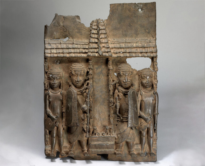 Artist unidentified, Relief plaque showing four page figures in front of palace compound, courtyard or altar entrance with high tiled roof and turret, c. 16th–17th century, brass, from Benin City, Edo Kingdom, Nigeria, 55 x 39 cm (© Trustees of the British Museum)