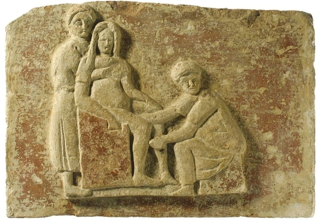 Relief sculpture showing Scribonia Attica sitting before a pregnant woman in a birthing chair, terracotta plaque, 28 x 41.5 cm (Museo Ostiense, Rome; photo: Parco Archeologico di Ostia Antica). Found in 1930 in the Isola Sacra necropolis, tomb 100