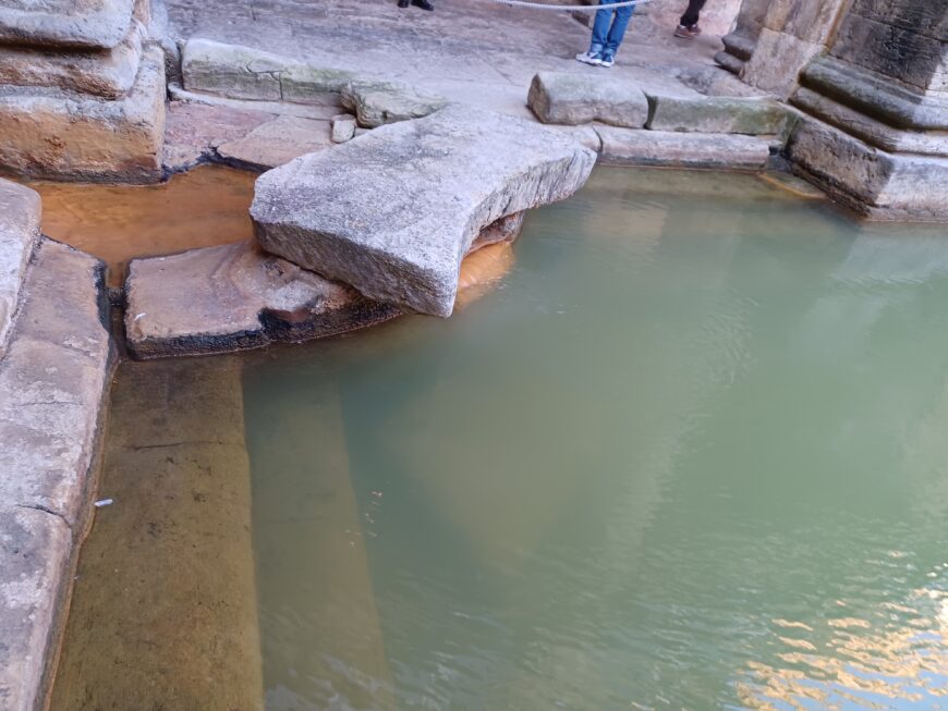 Northwest corner of the "Great Bath," where water flows in from the sacred spring. The steps into the pool are visible through the water (photo: Simon Burchell, CC BY-SA 4.0)