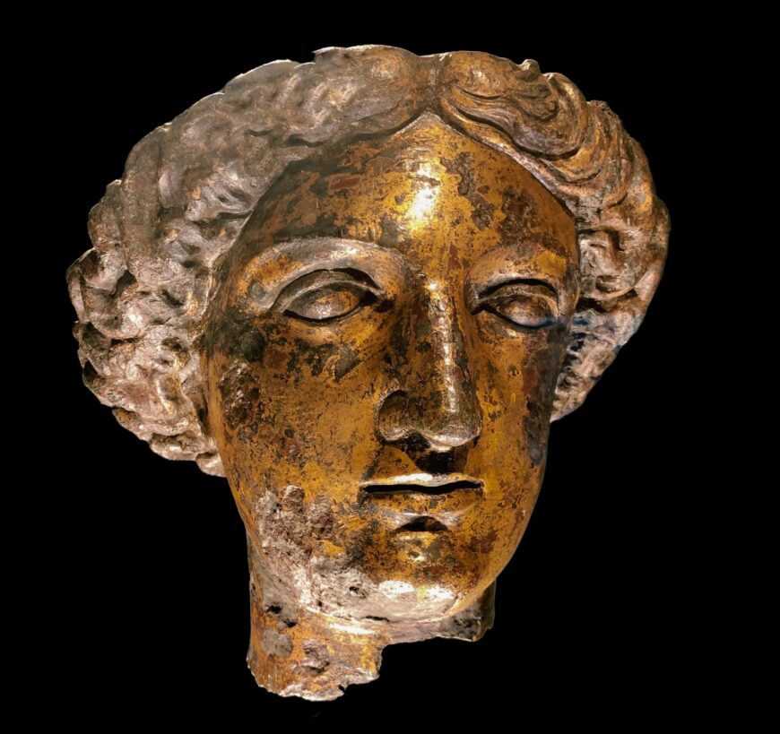 The surface shows signs of corrosion from the soil and damage from the statue's destruction in late antiquity. Head of the goddess Sulis Minerva, gilt bronze, c. 75 C.E. (Roman Baths Museum, Bath; photo: Wanda Marcussen, CC BY-NC-SA 4.0)