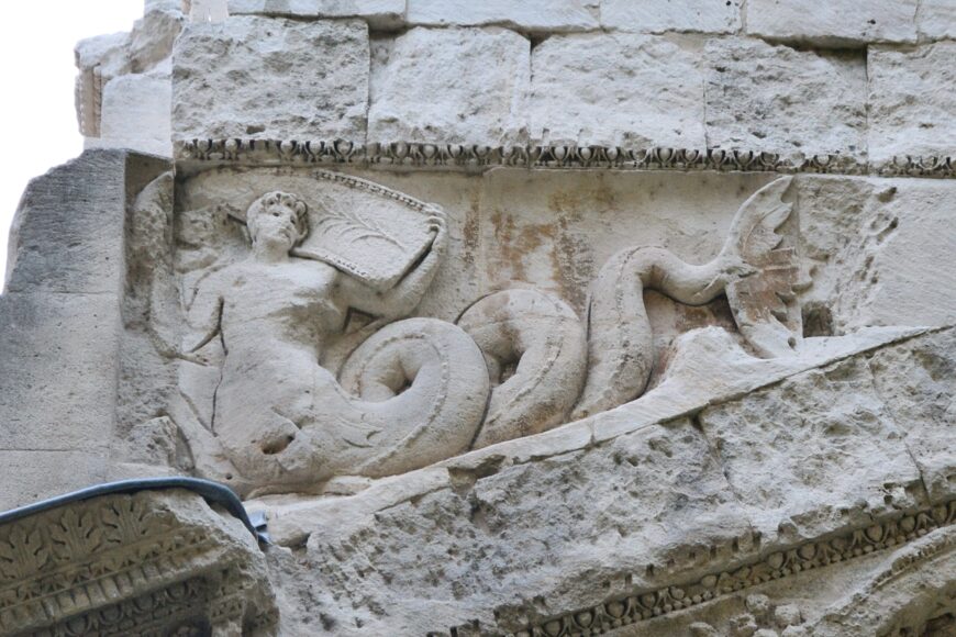 Triton (merman) holding part of a boat (detail), east end of the Arch at Orange, France, 20s B.C.E., stone, 19.21 x 19.57 x 8.4 m (photo: Marianne Casamance, CC BY-SA 3.0)