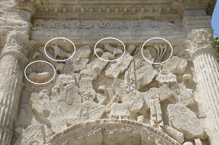 Weaponry sculptures with Celtic boar standards and carnykes (detail). Also visible are the battle frieze (above), the Corinthian columns (to either side), and the archivolt (archway) with egg-and-dart molding and a garland. Arch at Orange, France, 20s B.C.E., stone, 19.21 x 19.57 x 8.4 m (photo: Carole Raddato, CC BY-SA 2.0)